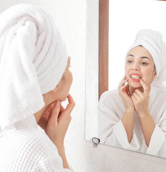 Woman looking at her teeth in bathroom mirror
