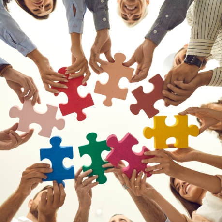 Group of people each holding a differently colored puzzle piece