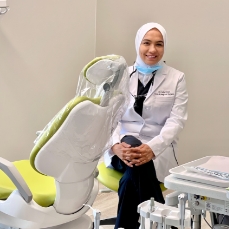 Doctor Khan smiling while sitting in periodontal treatment room