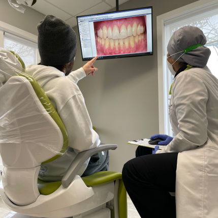 Doctor Khan showing a patient close up photos of their gums and teeth