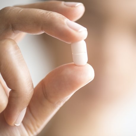 Close up of hand holding a white pill